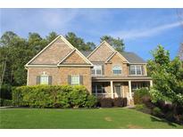 Inviting two-story brick home with a manicured lawn and charming front porch perfect for relaxing at 6570 Canyon Cv, Cumming, GA 30028