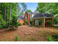 Charming brick home with mature landscaping and dark shutters on a lush, wooded lot at 1772 Benningfield Sw Dr, Marietta, GA 30064