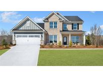 Inviting two-story home features a brick and siding exterior with a two-car garage and a well-manicured front lawn at 5350 Hyde Rd, Cumming, GA 30040