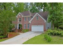 Charming two-story brick home with well-manicured lawn, mature trees, and attached two-car garage at 7435 Woodruff Way, Stone Mountain, GA 30087