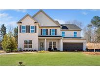 Two-story home with a well-manicured lawn, gray brick, black shutters, and a two-car garage at 5360 Hyde Rd, Cumming, GA 30040