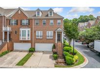Brick townhouse with two-car garage, manicured landscaping, and inviting front entrance, radiating curb appeal at 6054 China Rose Ln, Duluth, GA 30097