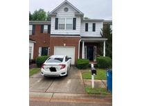 Two-story townhome with a brick facade, black shutters, and an attached garage and well-maintained landscaping at 116 Madeline Ct, Mcdonough, GA 30253