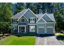 Charming two-story home with stone accents, a manicured lawn, and an attached two-car garage at 2015 Towne Lake W Hls, Woodstock, GA 30189