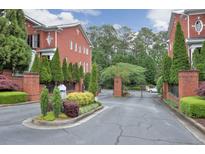 View of the gated entrance to a brick townhome community with manicured landscaping at 4298 Kingston Gate Cv, Chamblee, GA 30341