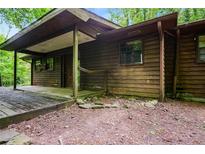 Rustic wood cabin exterior with a covered porch and natural surroundings in a wooded area at 418 Honey Suckle Ln, Stockbridge, GA 30281