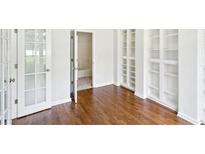 Bright bedroom with hardwood floors, built-in bookshelves, and french doors leading outside at 765 Brooks Cir, Stone Mountain, GA 30087