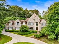 Elegant two-story home featuring a circular driveway and lush landscaping at 3905 Merriweather Woods, Johns Creek, GA 30022