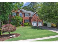 Charming two-story brick home featuring a well-manicured lawn, two-car garage, and classic architectural details at 320 Ironhill Trce, Woodstock, GA 30189