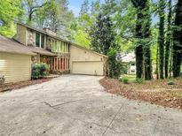 Stone and siding exterior of a home with an attached two-car garage and a long cracked concrete driveway at 10320 Crescent Ridge Dr, Roswell, GA 30076
