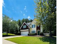 Inviting two-story home featuring manicured lawn, attached garage, and mature shade trees under a partly cloudy sky at 1600 Brisbane Drive, Dacula, GA 30019