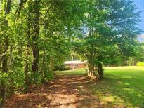 Scenic property entrance framed by lush trees and leads to a charming brick home on expansive lawn at 309 Cornish Mountain Rd, Oxford, GA 30054