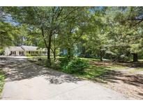 Ranch-style home with mature trees, spacious driveway, and inviting front porch at 4825 Rollins Dr, Powder Springs, GA 30127