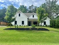 Charming, new construction, two-story home with a white exterior, dark windows and a well-manicured lawn at 3445 Henderson Dr, Cumming, GA 30041