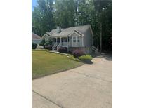 Charming two-story home with gray siding, landscaped yard, and inviting front porch and a view of the driveway at 72 Victorian Cir, Dallas, GA 30157