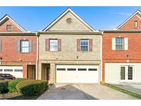 Charming townhome features a brick and tan facade, attached garage, and manicured landscaping at 7177 Fringe Flower Dr, Austell, GA 30168