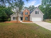 Charming two-story home featuring a manicured lawn, stone accents, and attached two-car garage at 834 Winding Grove Ln, Loganville, GA 30052
