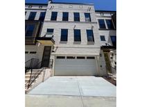 Modern townhome featuring a two-car garage, neutral brick facade, and elegant black window trim at 1107 Rivard Nw Cir, Atlanta, GA 30318
