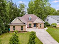 Charming brick home featuring a well-manicured lawn, a dormer window, and a long driveway at 5200 Woodmont Dr, Villa Rica, GA 30180