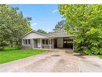 Charming single-story home with a gray brick facade, mature trees and a carport at 1176 Cardinal Ne Rd, Conyers, GA 30012