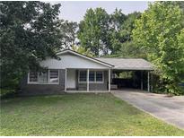 Charming single-story home with a covered parking area and a well-maintained front yard surrounded by mature trees at 1176 Cardinal Ne Rd, Conyers, GA 30012