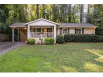 Charming brick home featuring a welcoming front porch and well-maintained lawn at 118 Lucia Dr, Smyrna, GA 30082