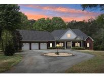 Beautiful brick home featuring a circular driveway, three-car garage, and manicured landscaping under a colorful sunset at 270 Morrow Rd, Newborn, GA 30056