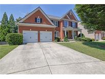 Traditional brick home featuring a two-car garage and well-maintained landscaping at 590 Kyle Trace Ct, Sugar Hill, GA 30518