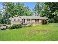 Charming single-story home featuring a brick facade, manicured lawn, and a convenient carport at 2714 Laurel Ridge Dr, Decatur, GA 30033