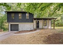 Charming split-level home featuring stone accents, a covered porch, and an attached garage at 5401 Martins Crossing Rd, Stone Mountain, GA 30088