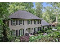 Charming brick home featuring mature landscaping, black shutters and a welcoming front entrance at 960 Lost Forest Dr, Sandy Springs, GA 30328
