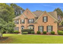 Stately brick home boasts manicured lawn, mature trees, and classic architectural details at 947 Summer Forest Drive, Suwanee, GA 30024