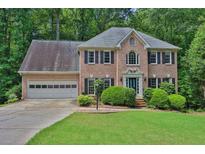 Charming two-story brick home with a manicured lawn and a two-car garage nestled among mature trees at 747 Mill Rock St, Lawrenceville, GA 30044