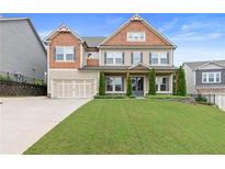 Charming two-story home featuring a manicured lawn, a two-car garage and inviting front porch at 411 Ridgeway Ln, Canton, GA 30114