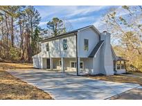Inviting two-story home featuring light gray siding, brick chimney, and a spacious driveway nestled among mature trees at 204 Elm St, Palmetto, GA 30268