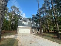 Charming two-story home with a gray siding, brick accents, and a two-car garage with ample treed front yard at 142 Tye St, Stockbridge, GA 30281