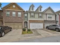 Charming townhome featuring a brick facade, a two-car garage, and a well-maintained lawn at 5661 Radford Loop, Fairburn, GA 30213