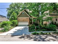 Charming home with a stone and siding exterior, lush landscaping, and a driveway leading to an attached garage at 1249 Francis Nw St, Atlanta, GA 30318