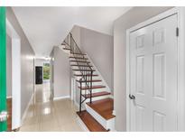 Inviting entryway showcasing wood stairs with metal railing and beige tile flooring at 2340 Beaver Ruin Rd # 68, Norcross, GA 30071