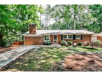 Charming brick home with a well-manicured lawn, mature trees, and cozy front porch with seating at 1082 Greenbriar Cir, Decatur, GA 30033