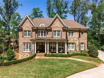 Stunning brick home featuring manicured landscaping, a stone walkway, and a welcoming front porch at 156 Lake Forrest Ne Ln, Atlanta, GA 30342