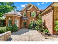 Charming brick home featuring a well-maintained landscaped front yard and a beautiful stone paver driveway at 5765 Riley Rd, Cumming, GA 30028