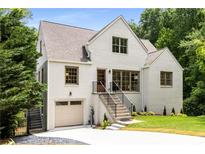 Charming white brick home featuring a well-manicured lawn, attached garage, and inviting staircase leading to the front door at 1327 Harvard Ne Rd, Atlanta, GA 30306