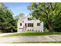 Charming white brick home featuring a landscaped yard, inviting entryway, and attached garage at 1327 Harvard Ne Rd, Atlanta, GA 30306
