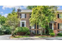 Charming two-story brick townhome featuring black shutters and lush landscaping at 3532 Paces Nw Pl, Atlanta, GA 30327