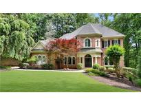 Charming two-story brick home with a manicured lawn, mature trees and professionally landscaped front yard at 5040 Harrington Rd, Johns Creek, GA 30022