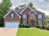 Charming two-story brick home with black shutters, a well-manicured lawn, and a two-car garage at 6765 Crofton Dr, Alpharetta, GA 30005