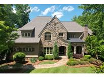 Stunning stone home featuring manicured landscaping, arched entryway, and a charming walkway to the front door at 1023 Little Darby Ln, Suwanee, GA 30024