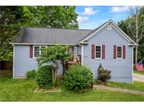 Charming one-story home featuring light blue siding, red shutters, and mature landscaping at 7920 Silversmith Dr, Cumming, GA 30028