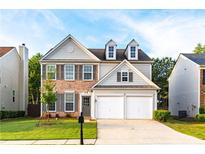 Charming two-story home with brick accents, dormer windows, a two-car garage, and a well-manicured front yard at 8750 Radford Ln, Suwanee, GA 30024